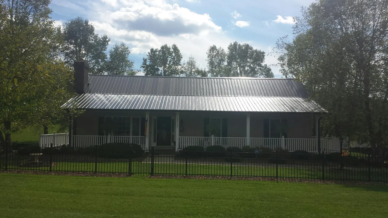 Gray metal roof on a brick ranch with a full width front porch — Gutter Guard Installation work by our crew in Sharpsville